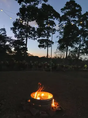 a fire pit in a field with trees in the background at Tropical Crystal House in Guápiles