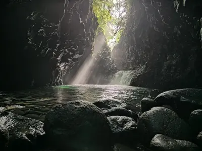 a waterfall in a cave with rocks in the water at Tropical Crystal House in Guápiles