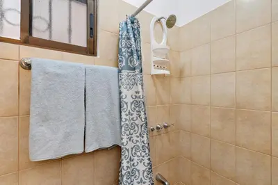 a bathroom with a shower with towels and a window at 2-BD Condo with Pool, Walk to Beach in Coco