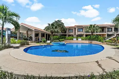 a swimming pool in front of a building at 2-BD Condo with Pool, Walk to Beach in Coco