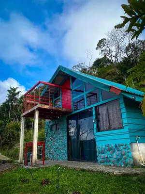 a blue house with a balcony on top of it at Finca Buena Vista in Turrialba
