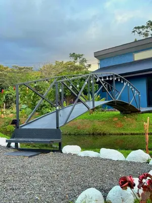 a metal bridge over a river in front of a building at Casa del Lago in Bijagua