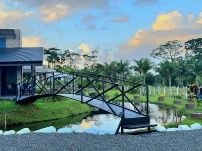 a bridge over a river with a bench in a park at Casa del Lago in Bijagua