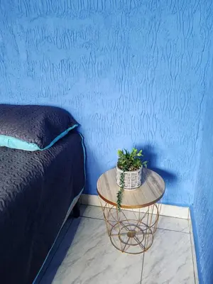 a blue bedroom with a table with a bed and a blue wall at YAIZA HOUSE Jaco in Jacó
