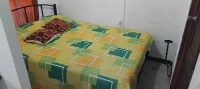 a bed with a colorful comforter and two pillows at La casita de Antonio en Sarapiqui in Llano Grande