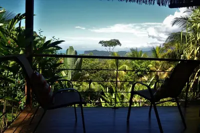 a balcony with two chairs and a view of the jungle at Chalet Jardin Tropical in Ojochal