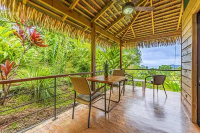 a dining room with a table and chairs on a balcony at Chalet Jardin Tropical in Ojochal
