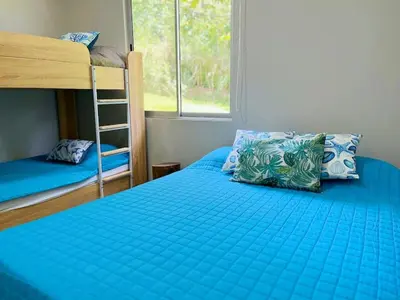 a bedroom with two bunk beds and a blue comforter at Casa Ballena with Beach Access and Private Pool in Uvita