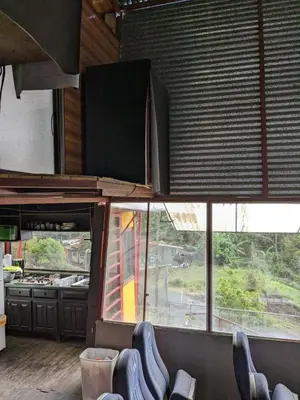 a restaurant with chairs in a room with windows at Alojamiento el Mirador in Tapantí