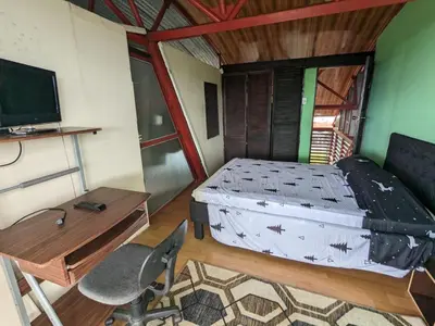 a bedroom with a bed and a desk and a television at Alojamiento el Mirador in Tapantí