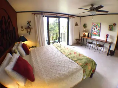 a bedroom with a large bed and a balcony at Lucky Bug Bed And Breakfast in Nuevo Arenal