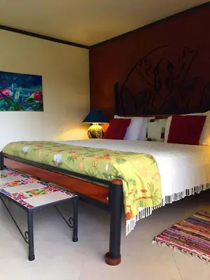 a bedroom with a large bed and a table at Lucky Bug Bed And Breakfast in Nuevo Arenal