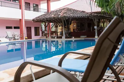 a swimming pool with a chair and an umbrella at Hotel Nany in Brasilito