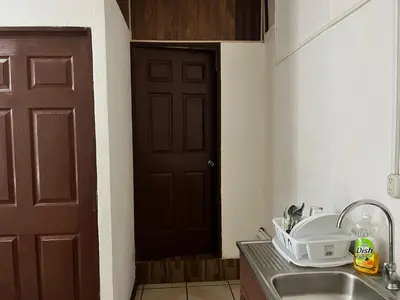 a kitchen with a sink and a brown door at Este no 3 habitaciones in Siquirres