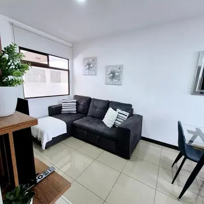 a living room with a black couch and a window at Moderno apartamento en San Jose CR in San José