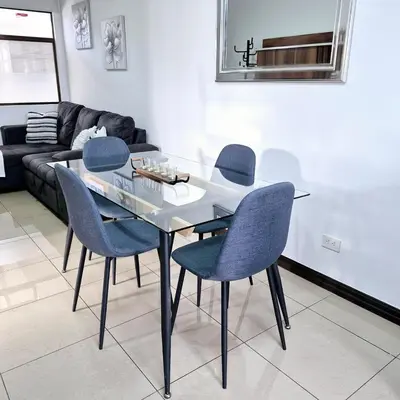 a dining room with a glass table and blue chairs at Moderno apartamento en San Jose CR in San José