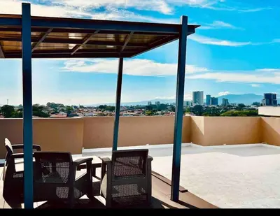 a patio with two chairs and a table on a roof at Moderno apartamento en San Jose CR in San José