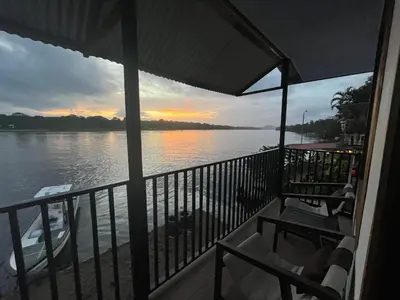 a balcony with a view of the water at sunset at Apartamento Lirios del Río in Tortuguero