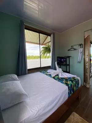 a bedroom with a bed and a large window at Apartamento Lirios del Río in Tortuguero