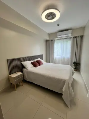 a bedroom with a white bed with a window and a bed sqor at Refugio Caribeño in Puerto Limón