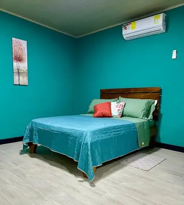 a bedroom with a bed with a blue wall at Paraiso En-suite #3 in Parrita
