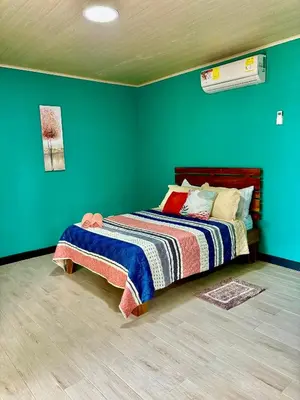 a bedroom with a bed with a green wall at Paraiso En-suite #3 in Parrita
