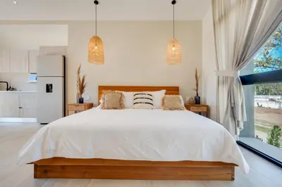 a bedroom with a white bed and a large window at The Bungalows Flamingo - 10 Unit Boutique Hotel in Playa Flamingo