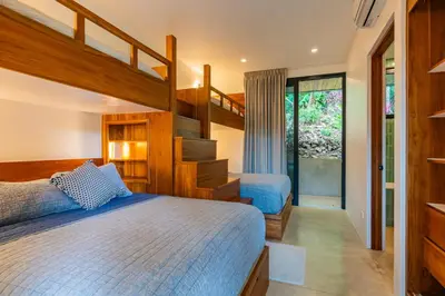 a bedroom with two beds and a staircase at Casa Rocky Point in Nosara