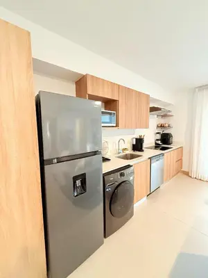 a kitchen with a stainless steel refrigerator and wooden cabinets at Viva Jaco Unit 0605 in Jacó
