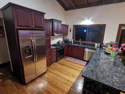 a kitchen with a stainless steel refrigerator and wooden cabinets at Mountain View Near SJO Airport Fast WiFi in Alajuela City