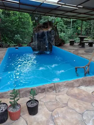 a swimming pool with a waterfall in a backyard at Cabaña escondida Venecia in Venecia