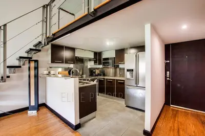 an open kitchen with a staircase in a loft at CR MARIPOSA RENTALS lakeview, spacious penthouse with office, pool, gym, Jacuzzi in Santa Ana
