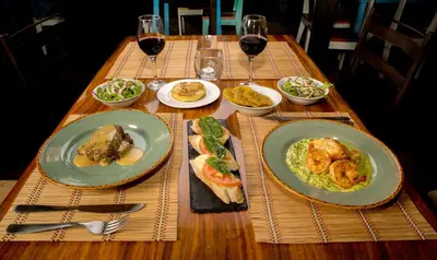 a wooden table with plates of food and glasses of wine at Chayote Lodge in Zarcero