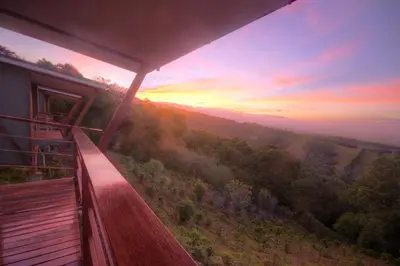 a balcony of a house with a view of a forest at Chayote Lodge in Zarcero