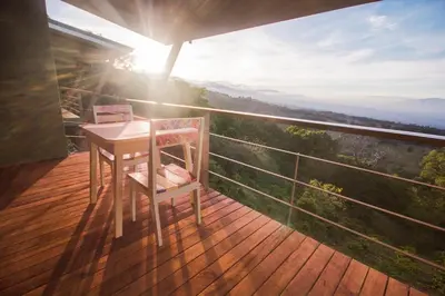 a wooden deck with a table and chair on a balcony at Chayote Lodge in Zarcero