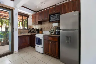 a kitchen with wooden cabinets and a white refrigerator at Coco - Laguna Azul Poolside Condo in Coco