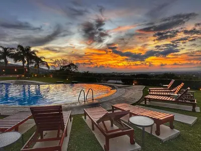 a pool with chairs and a sunset in the background at CR MARIPOSA RENTALS Brand New lake view Penthouse with office space in Santa Ana
