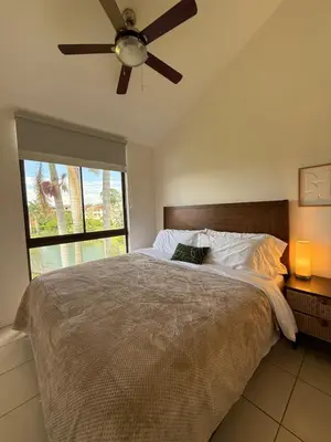 a bedroom with a bed with a ceiling fan and a window at CR MARIPOSA RENTALS Brand New lake view Penthouse with office space in Santa Ana