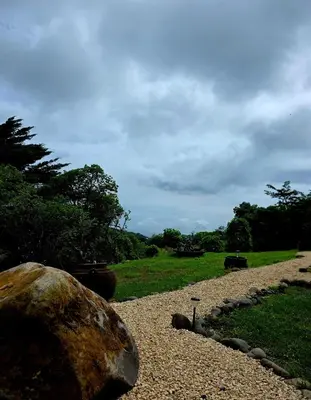 a rock sitting on a gravel road next to a field at Sea song cabin with private waterfall and river in Monteverde Costa Rica