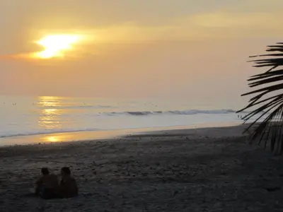 two people sitting on the beach watching the sunset at Casa Esmeralda in Paquera