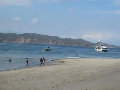 a group of people on a beach with boats in the water at Casa Esmeralda in Paquera