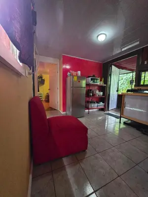 a living room with a red chair and a refrigerator at CocoRelax in Siquirres