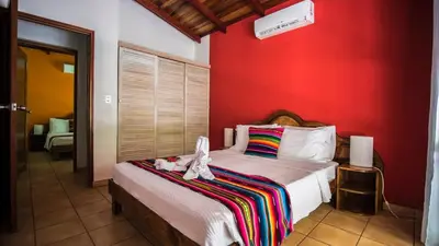 a bedroom with a bed with a red wall at Hotel El Pequeño Gecko Verde in Sámara