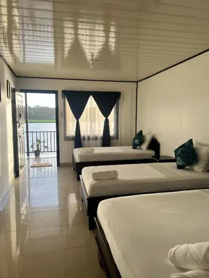 a bedroom with three beds and a balcony at Hotel Angsa River View Tortuguero in Tortuguero