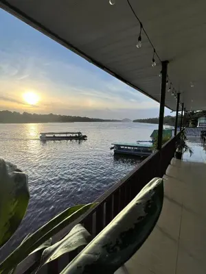 a boat on a lake with a dock in the water at Hotel Angsa River View Tortuguero in Tortuguero