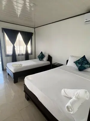 a bedroom with two beds and two windows at Hotel Angsa River View Tortuguero in Tortuguero