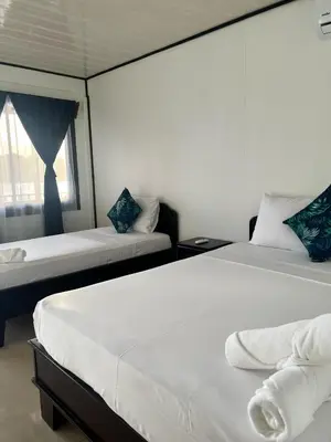 two beds in a room with a window at Hotel Angsa River View Tortuguero in Tortuguero