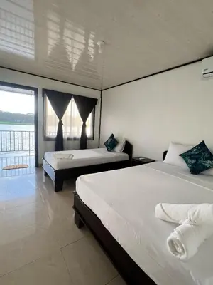 a bedroom with two beds and a large window at Hotel Angsa River View Tortuguero in Tortuguero