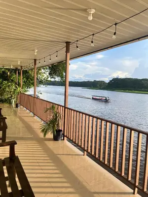 a porch with a view of the water and a boat at Hotel Angsa River View Tortuguero in Tortuguero