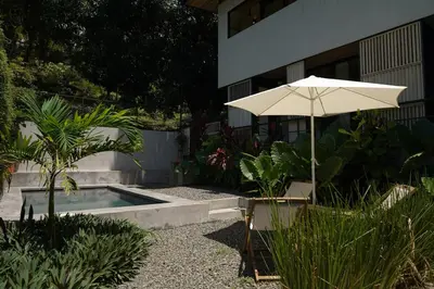 an umbrella and a chair next to a swimming pool at VED Beach Deluxe Studio 2, Steps to the Beach in Santa Teresa Beach